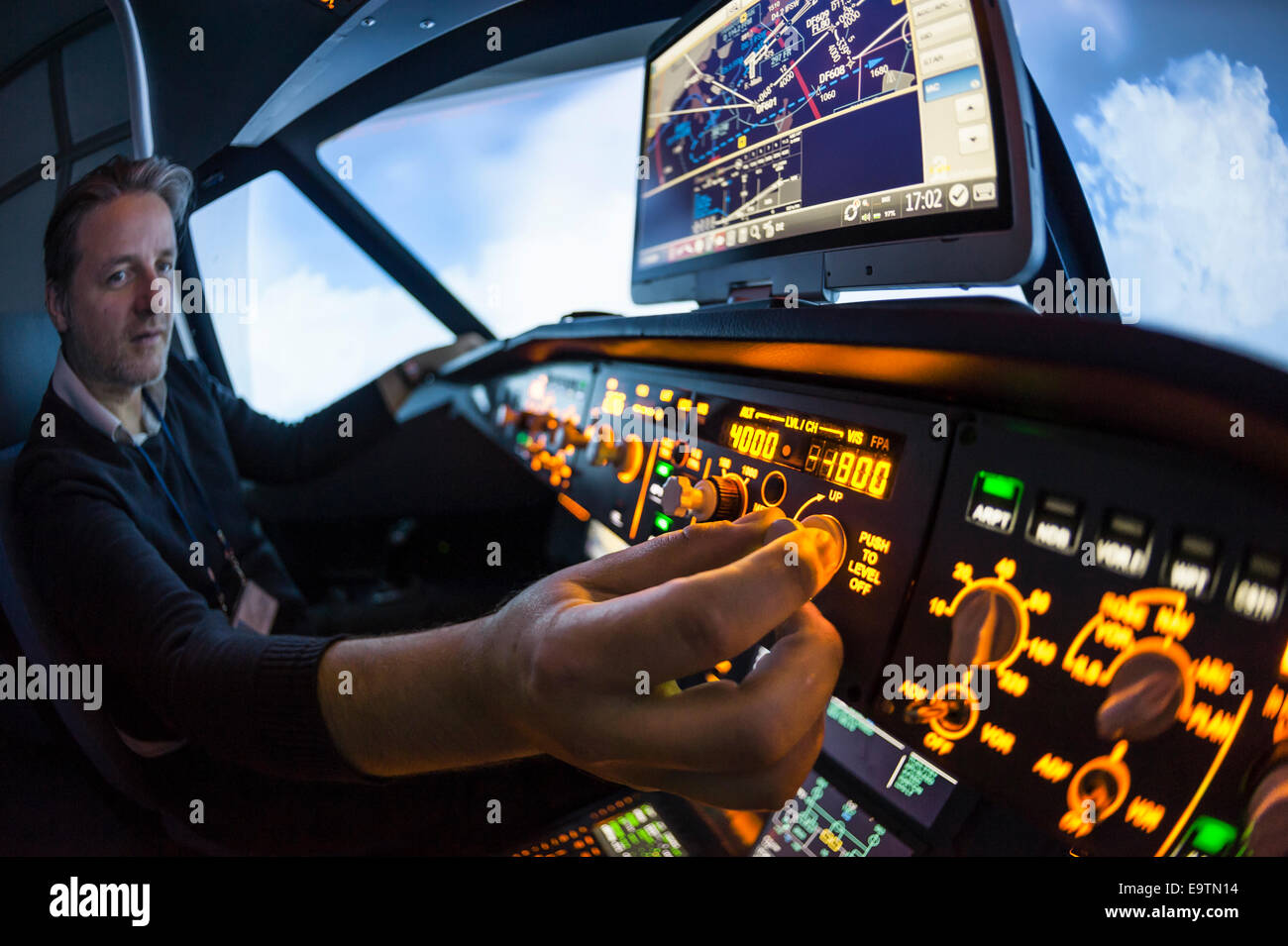 Cockpit of an Airbus A320 flight simulator that is used for training of professional airline pilots (pilot adjusting autopilot) Stock Photo