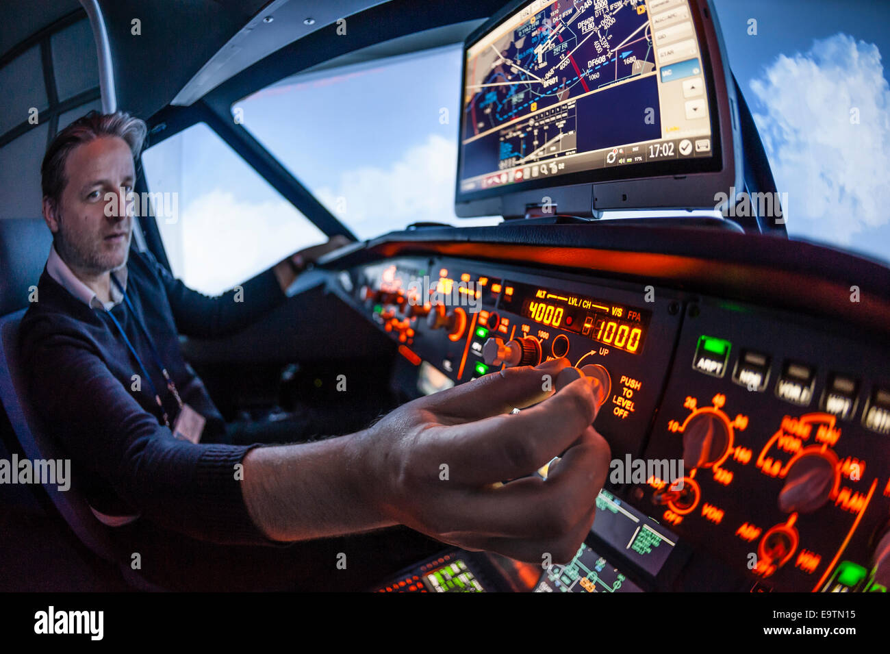 Cockpit of an Airbus A320 flight simulator that is used for training of professional airline pilots (pilot adjusting autopilot) Stock Photo