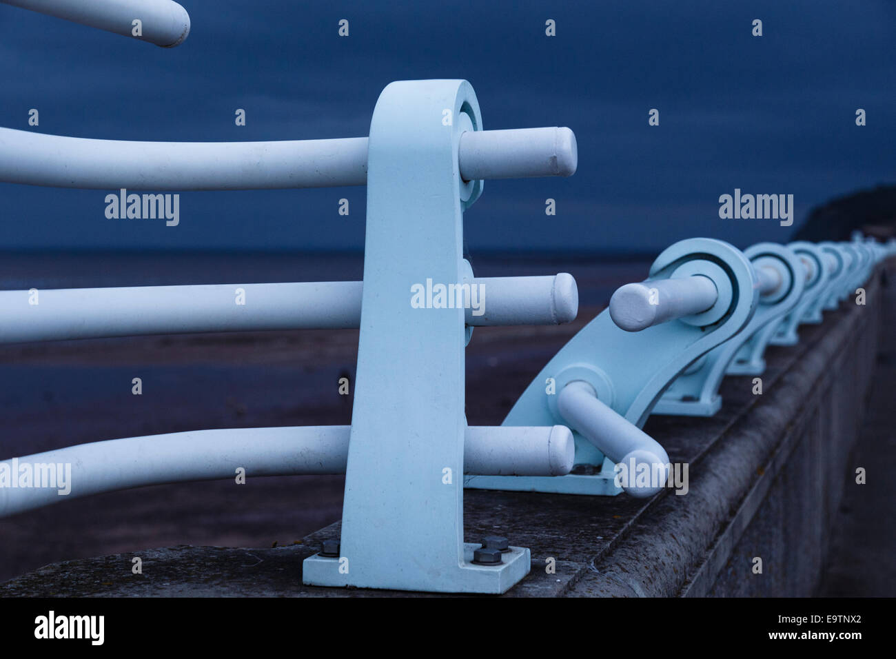 Blue railings on sea wall contrasting with dark sky Stock Photo - Alamy