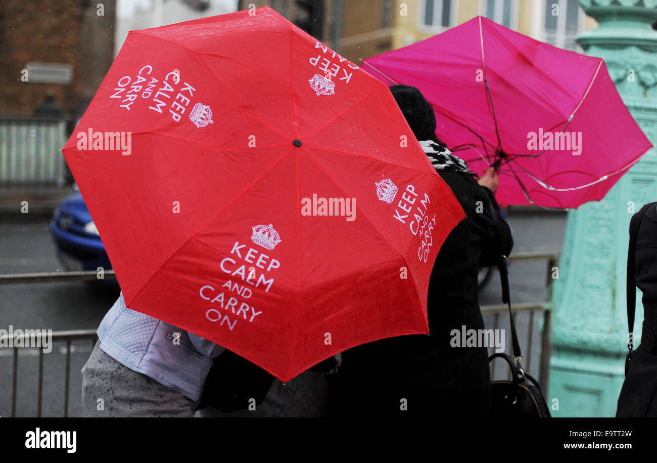 A woman struggles with her red 'Keep Calm and Carry On' umbrella along
