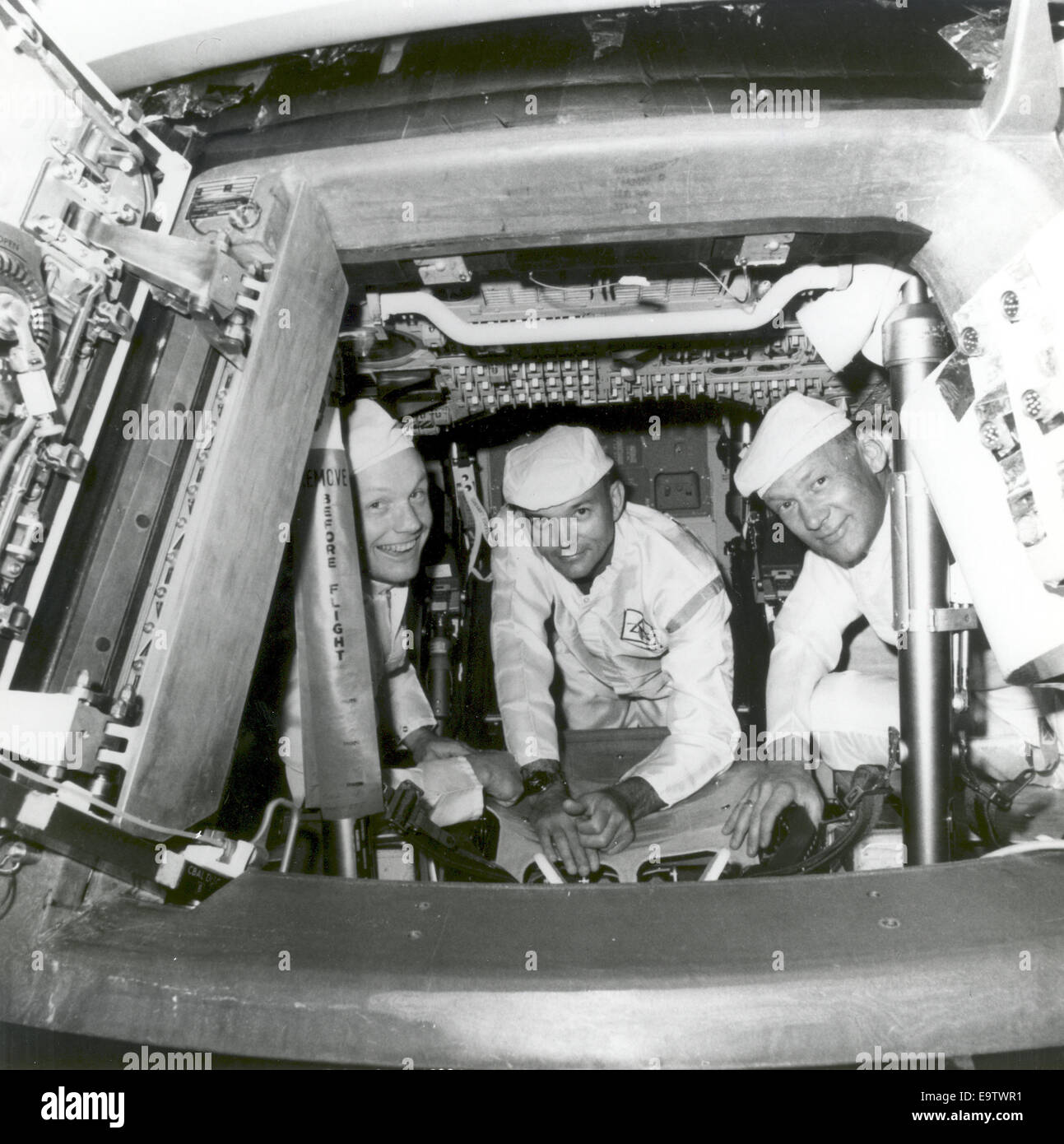 The Apollo 11 crew conducting a crew compartment fit and functional check, of the equipment and storage locations, in their command module. Peering from the hatch are from left, Neil Armstrong, commander; Michael Collins, command module pilot; and Buzz Al Stock Photo