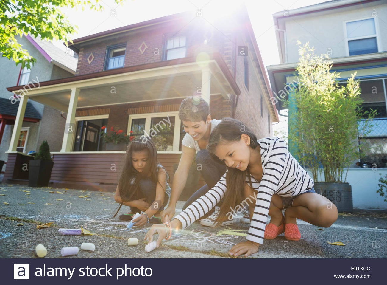 Mother and daughters drawing with sidewalk chalk Stock Photo