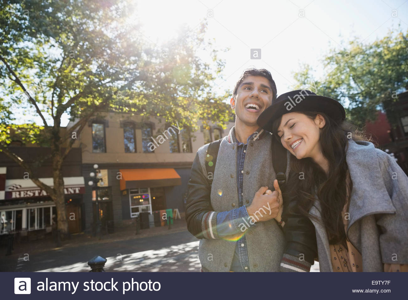 Couple laughing on sunny urban street Stock Photo