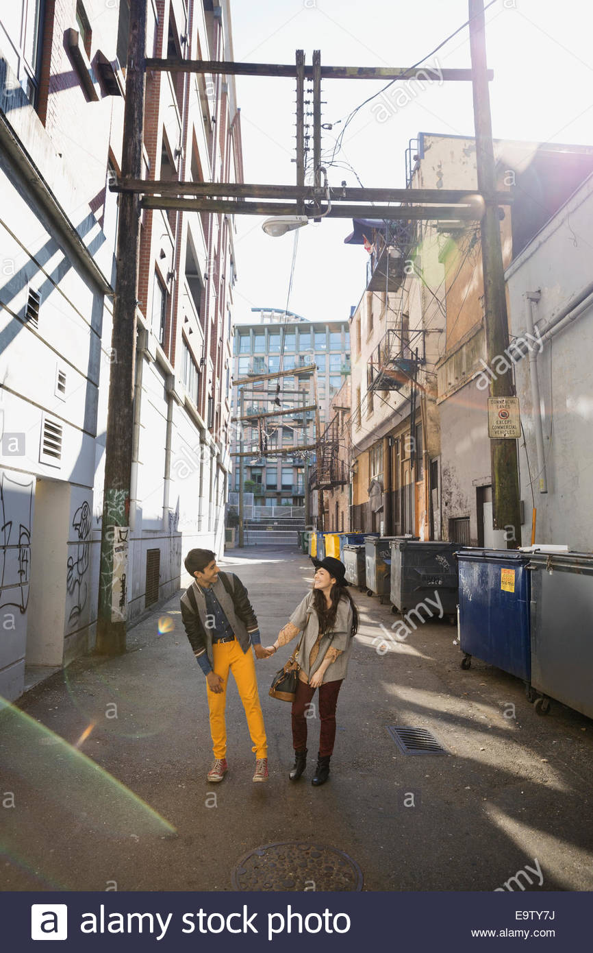 Couple holding hands in urban alley Stock Photo