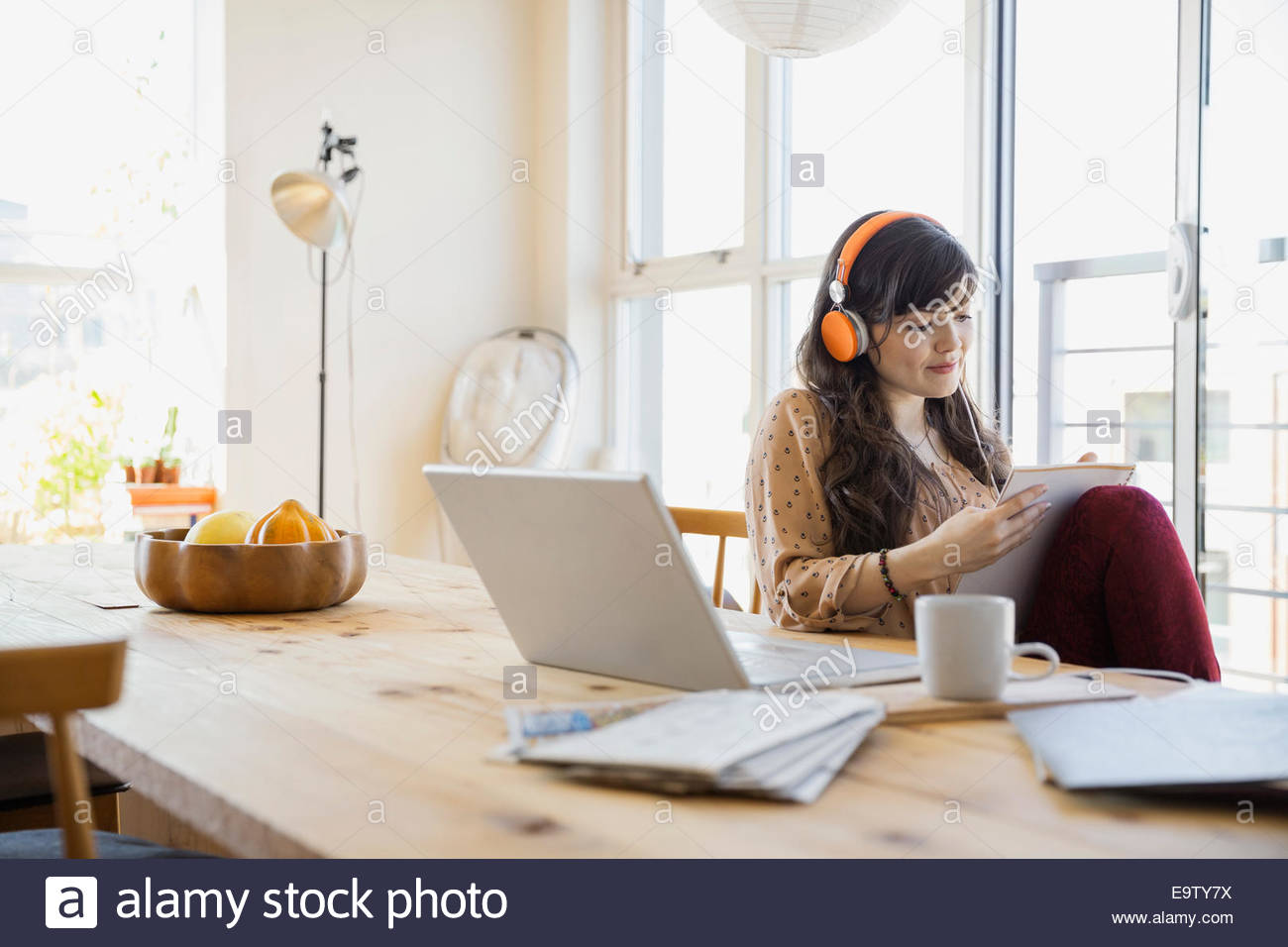 Woman with headphones and notebook at laptop Stock Photo