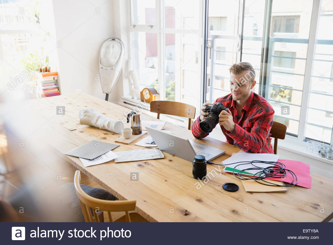 Photographer with camera uploading to laptop at tale Stock Photo