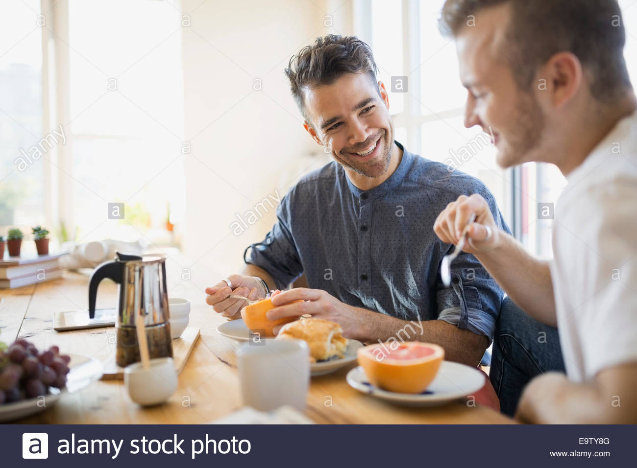 Homosexual couple enjoying breakfast at table Stock Photo
