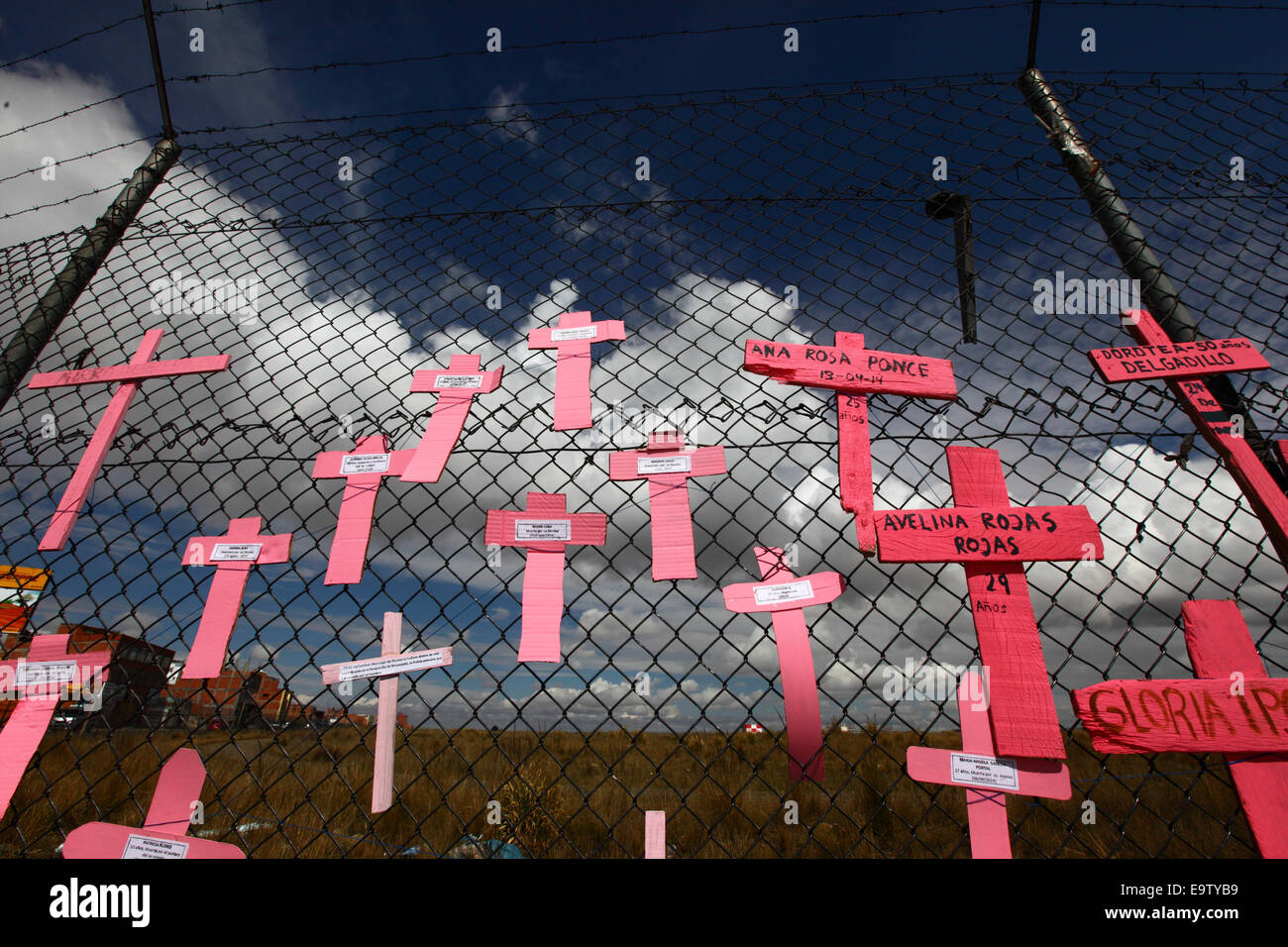 EL ALTO, BOLIVIA, 2nd November 2014. Crosses with the names of women against the sky on a wire mesh fence, part of a memorial for recent victims of femicide and domestic violence against women. According to a WHO report in January 2013 Bolivia is the country with the highest rate of violence against women in Latin America. Credit: James Brunker / Alamy Live News Stock Photo