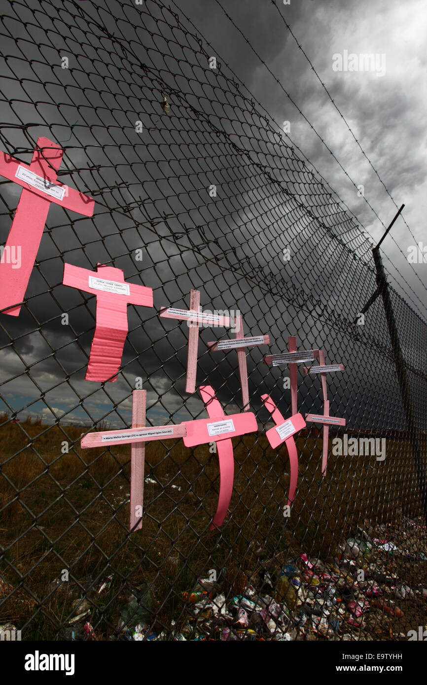 EL ALTO, BOLIVIA, 2nd November 2014. Crosses with the names of women against dark skies on a wire mesh fence, part of a memorial for recent victims of femicide and domestic violence against women. According to a WHO report in January 2013 Bolivia is the country with the highest rate of violence against women in Latin America. Credit: James Brunker / Alamy Live News Stock Photo