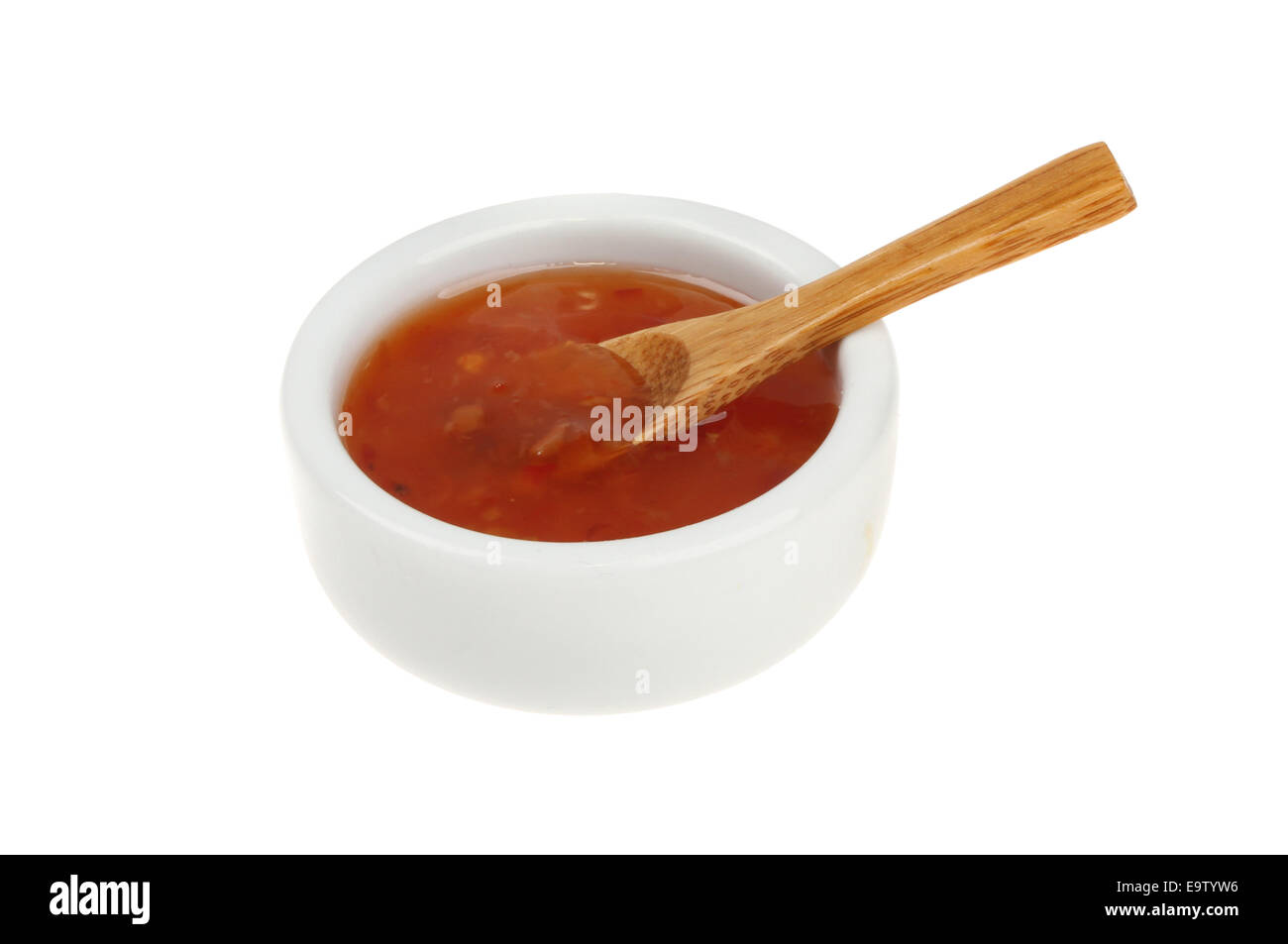 Sweet chilli dipping sauce in a ramekin with a wooden spoon isolated against white Stock Photo