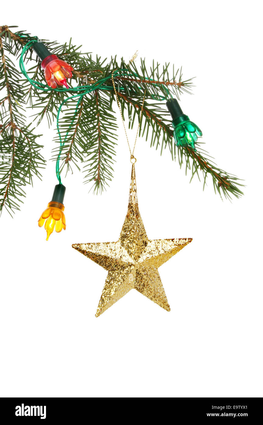 Gold star ornament hanging in a Christmas tree with lights against a ...