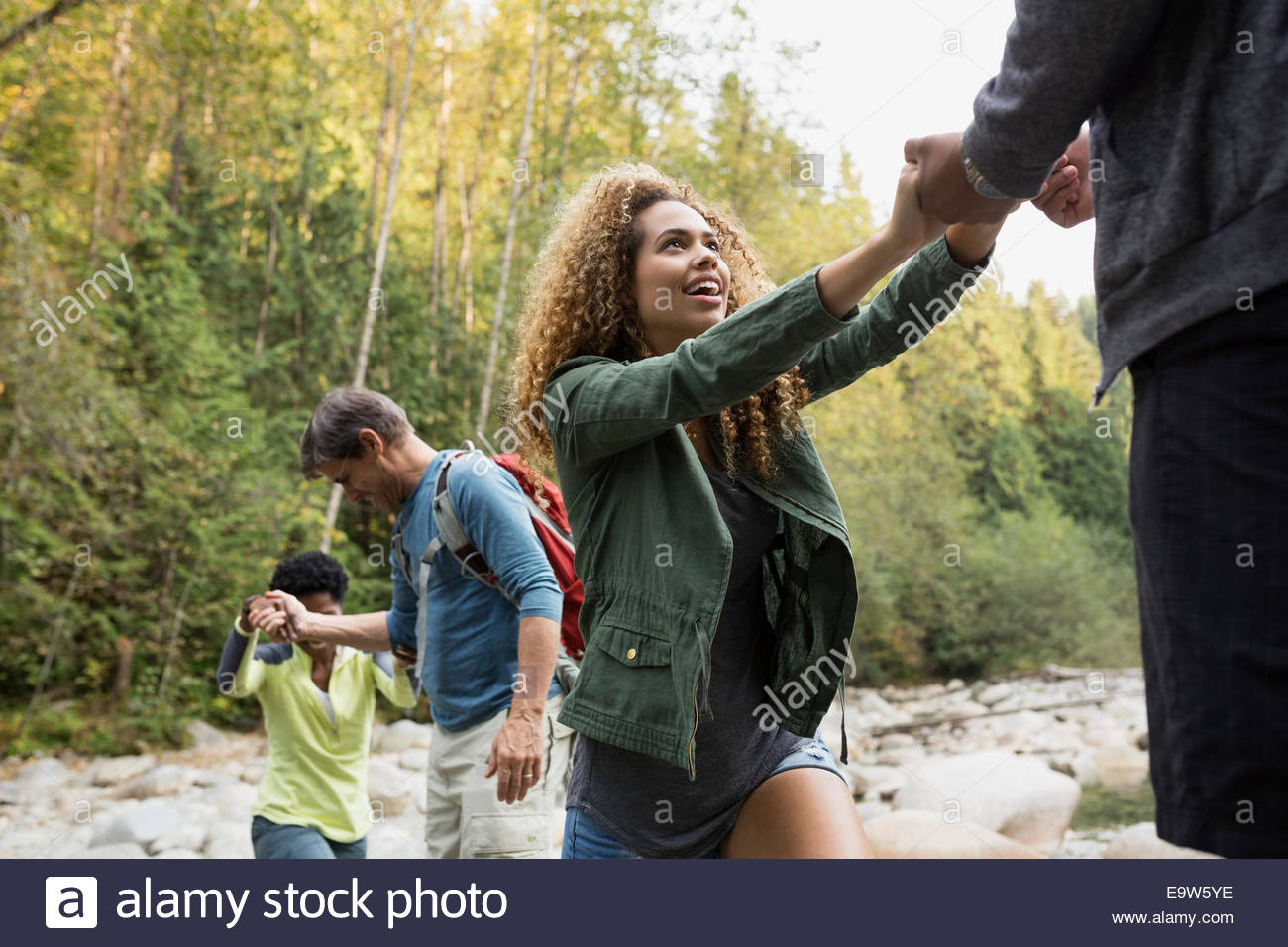 Friends crossing rocks over creek in woods Stock Photo Alamy