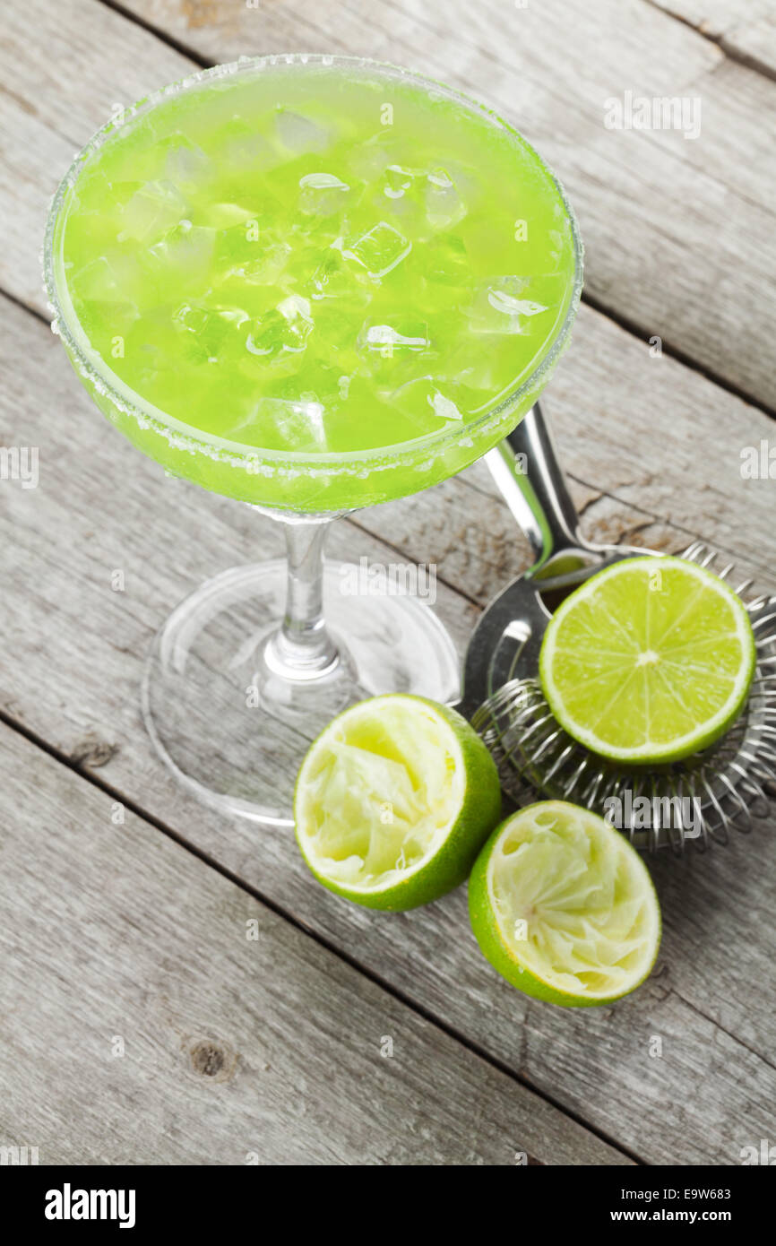 Classic margarita cocktail with salty rim on wooden table with limes ...