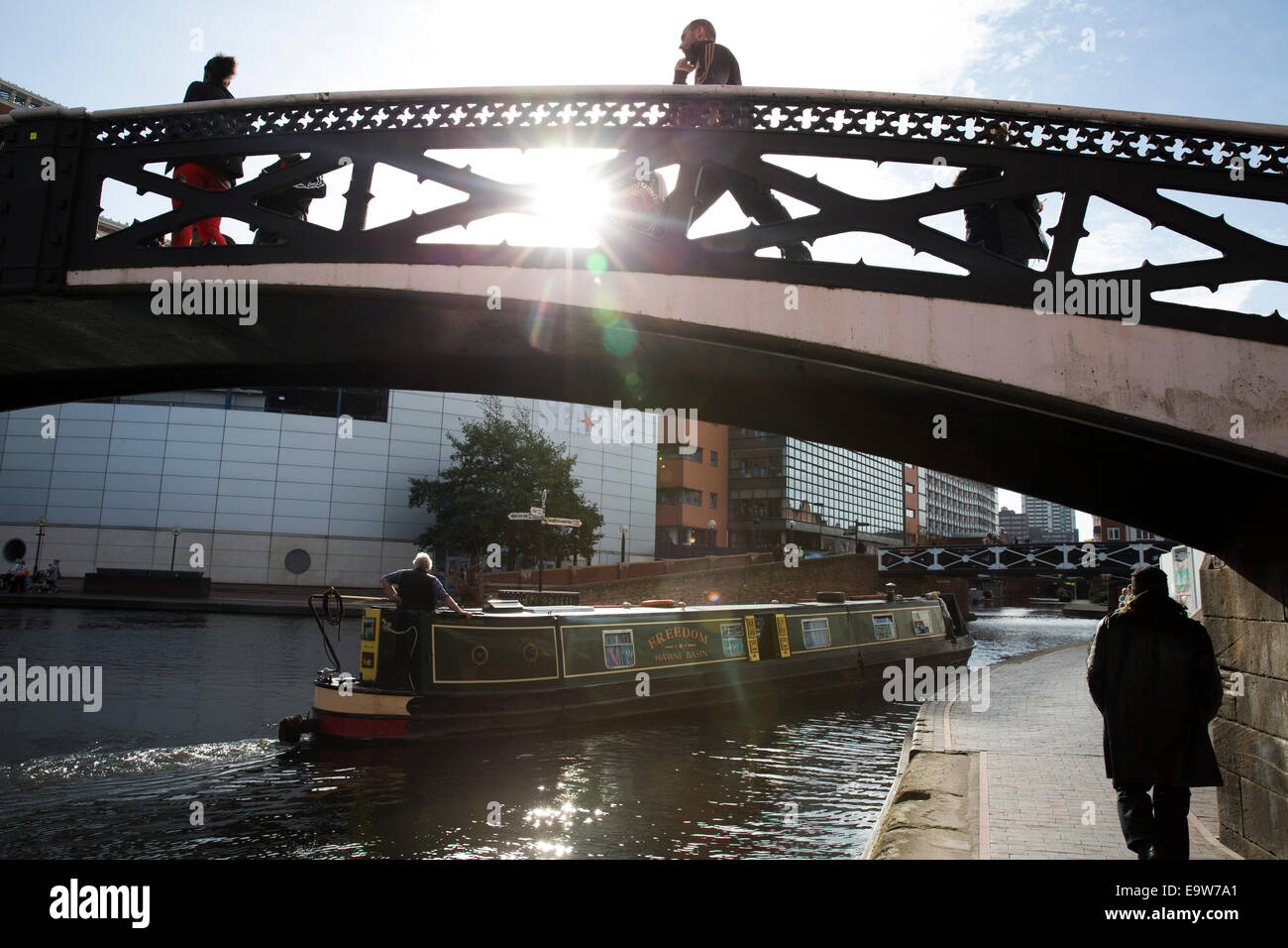 A narrow boat passes under a bridge over the Birmingham Old Line Canal outside the NIA in Brindleyplace, Birmingham City Centre Stock Photo