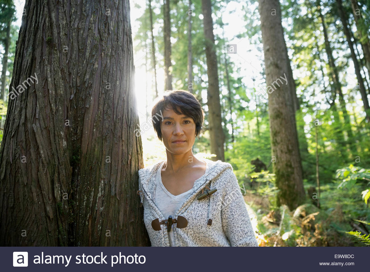 Portrait of confident woman leaning against tree Stock Photo