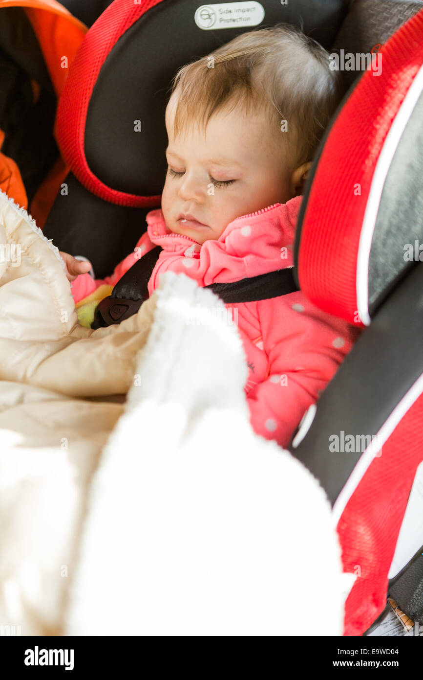 Cute baby girl sleeping in her car seat while traveling in the car