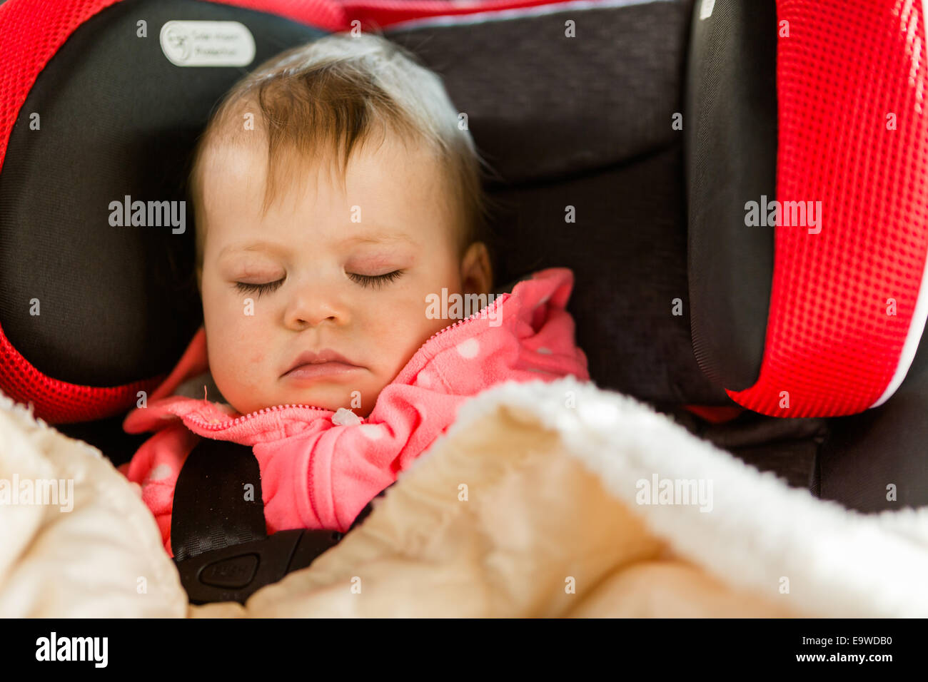 Cute baby girl sleeping in her car seat while traveling in the car