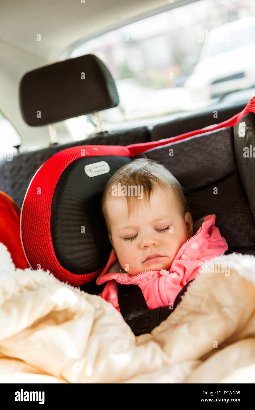 Cute baby girl sleeping in her car seat while traveling in the car