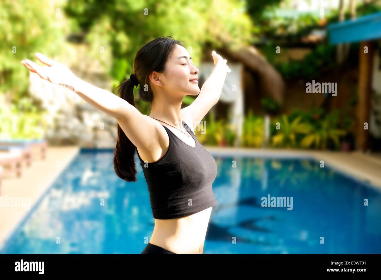 Asian Girl open arms in fitness outfit relaxing at pool Stock Photo