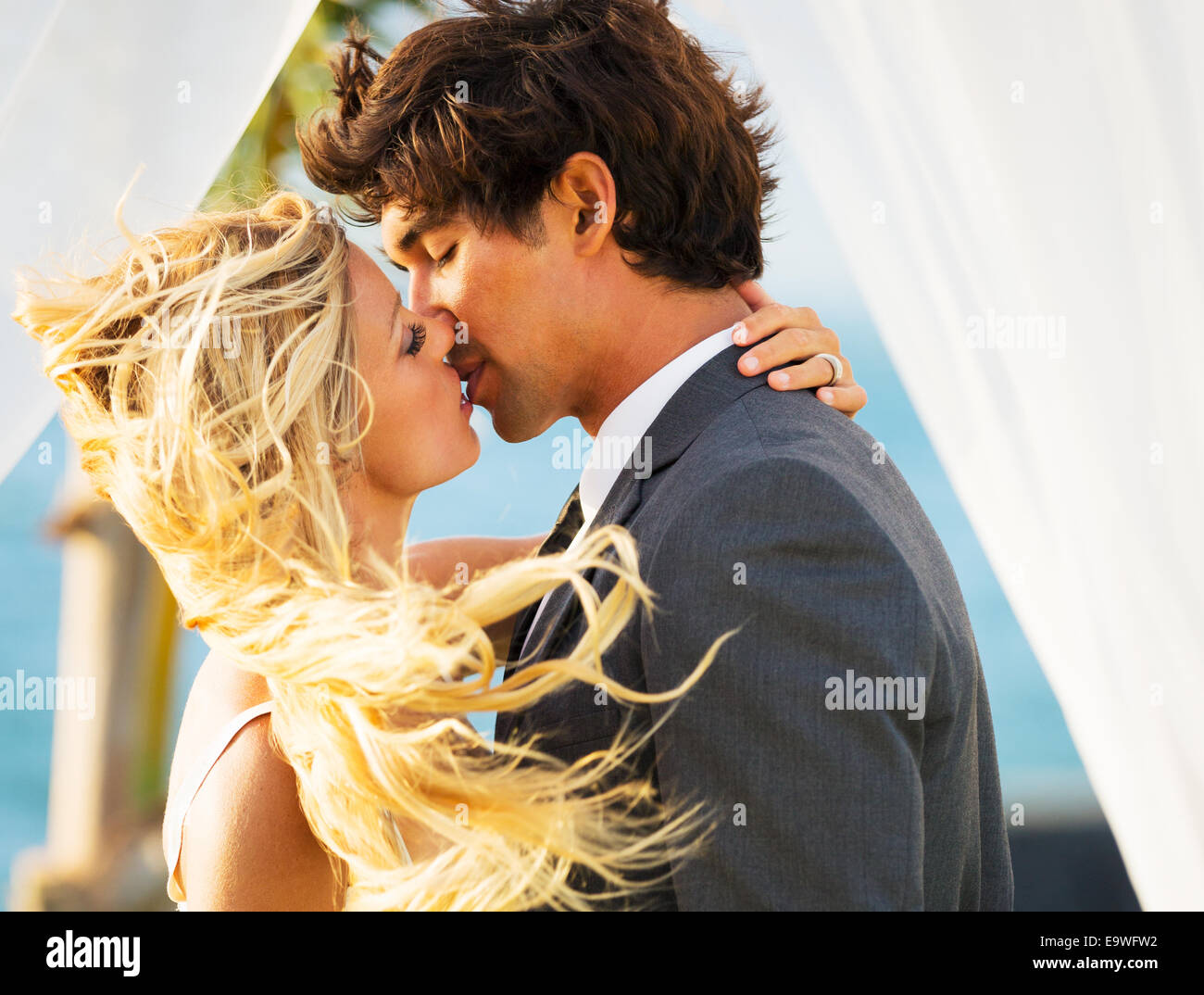 Wedding, Beautiful Romantic Bride and Groom Kissing and Embracing at Sunset Stock Photo