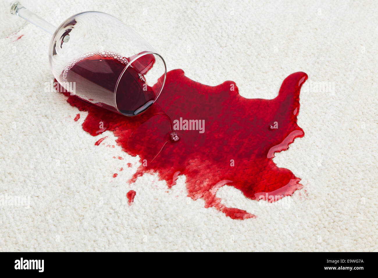 Red wine is spilled on a carpet. Glass fallen over Stock Photo