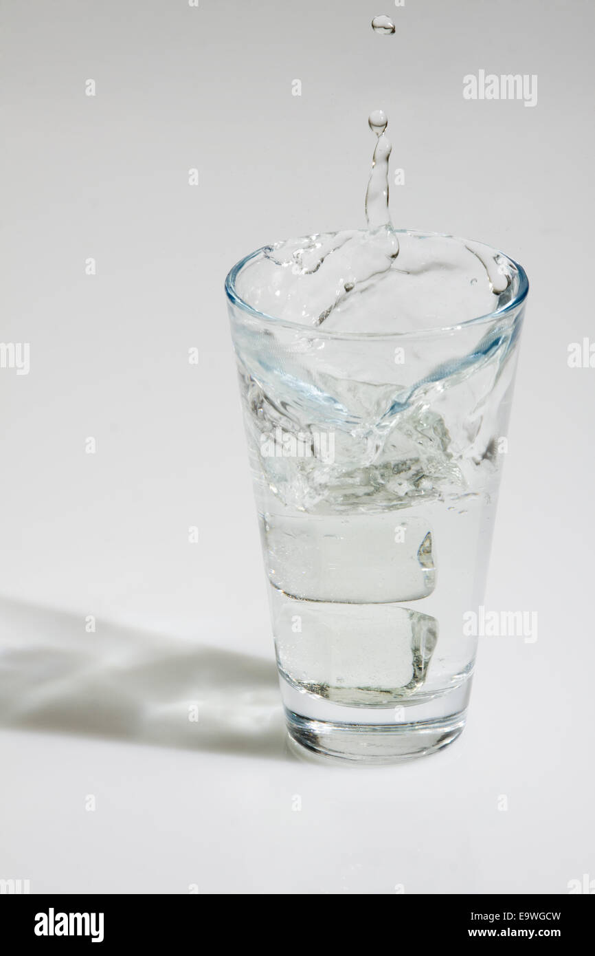 Ice cubes falling into a glass of water Stock Photo - Alamy