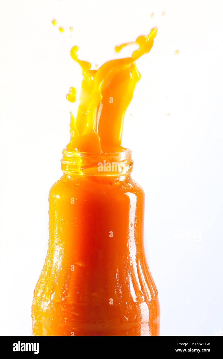 Carrot juice squirts out of the bottle Stock Photo