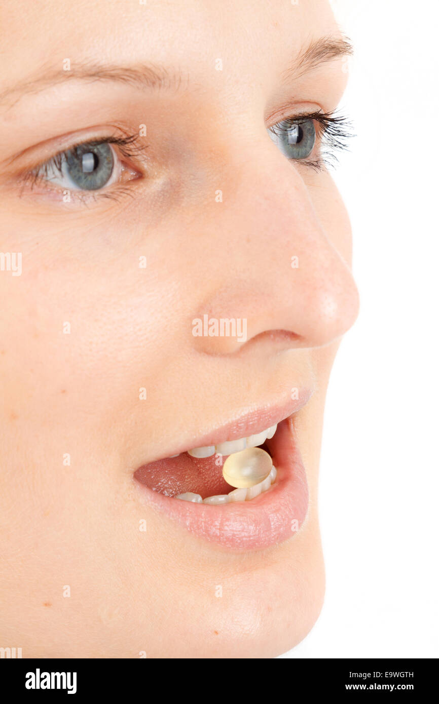 Young woman with a pill between the teeth Stock Photo