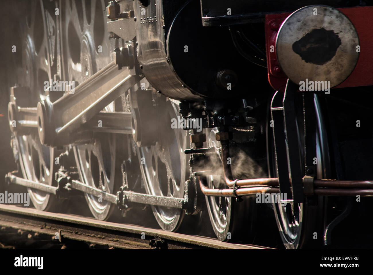 Backlit close up of the wheels of Tangmere, an approaching steam engine train. (Train SR Light Pacific 4-6-2 no 34067) Stock Photo