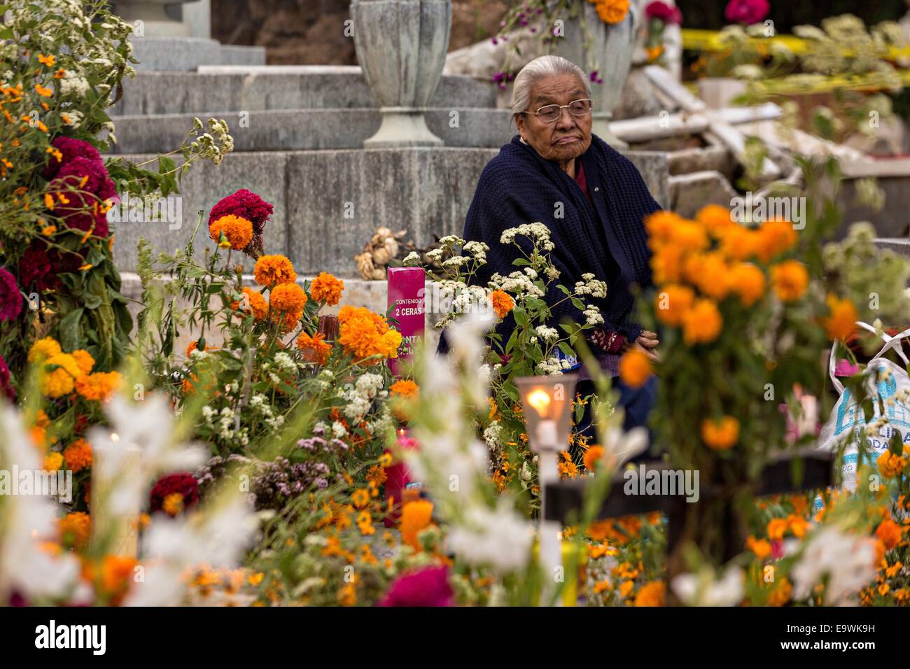 Oaxaca, Mexico. 29th Oct, 2014. An elderly woman reflects at the gravesite of her deceased husband at Xoxocatian cemetery decorated with flowers and candles for the Day of the Dead Festival known in spanish as D'a de Muertos. © Richard Ellis/ZUMA Wire/ZUMAPRESS.com/Alamy Live News Stock Photo