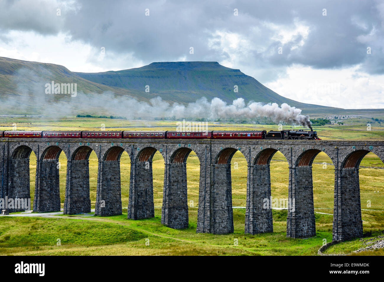 Steam train crossing the Ribblehead Viaduct on the Settle-Carlisle railway line with Ingleborough behind Stock Photo