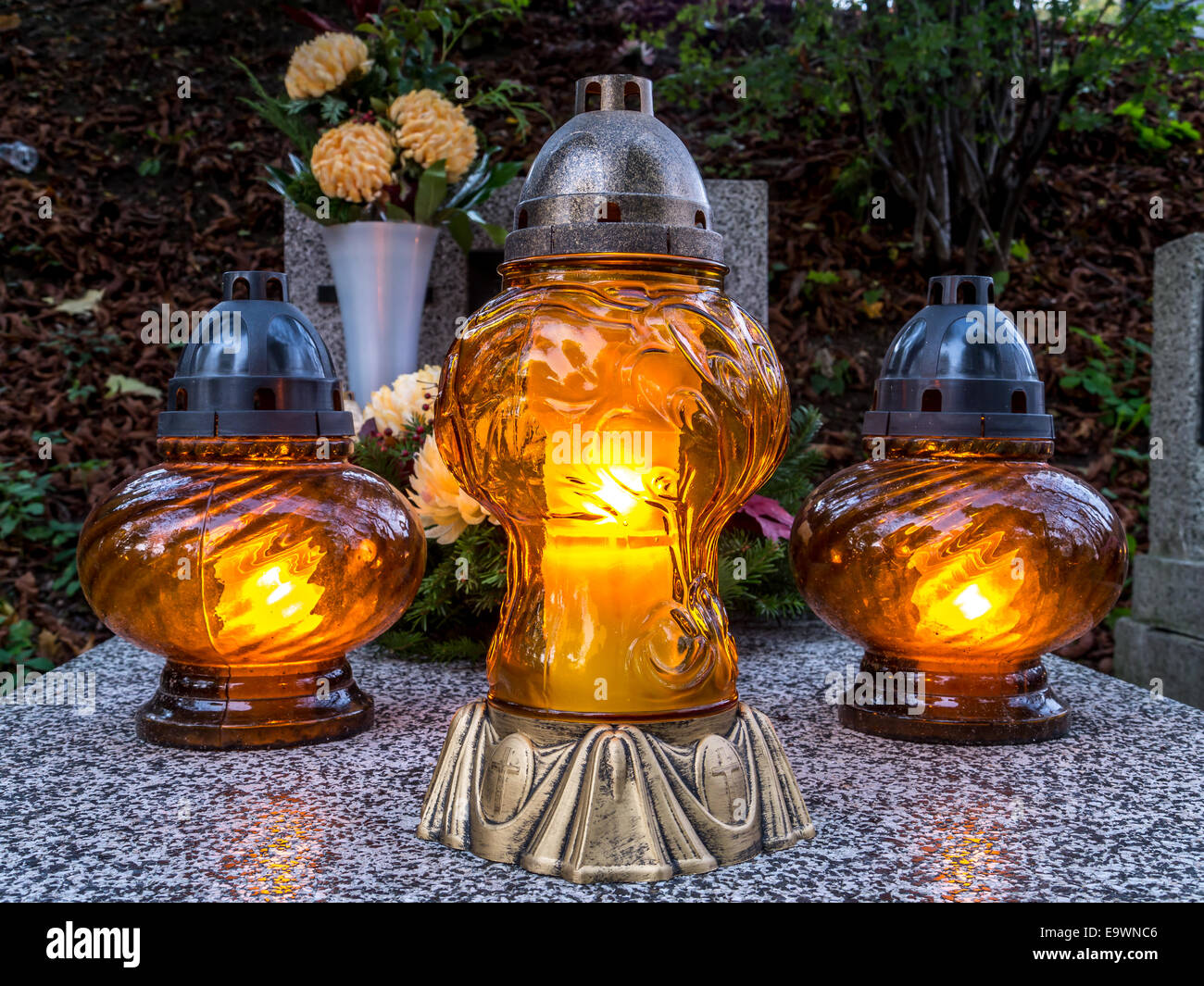 Votive candles lit on tombstone Stock Photo