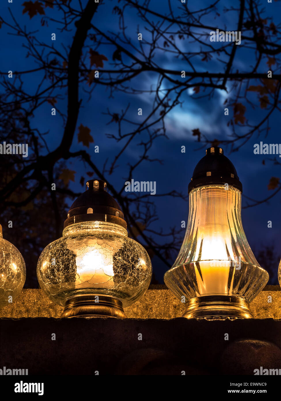 Votive candles lit on tombstone against dusk sky Stock Photo