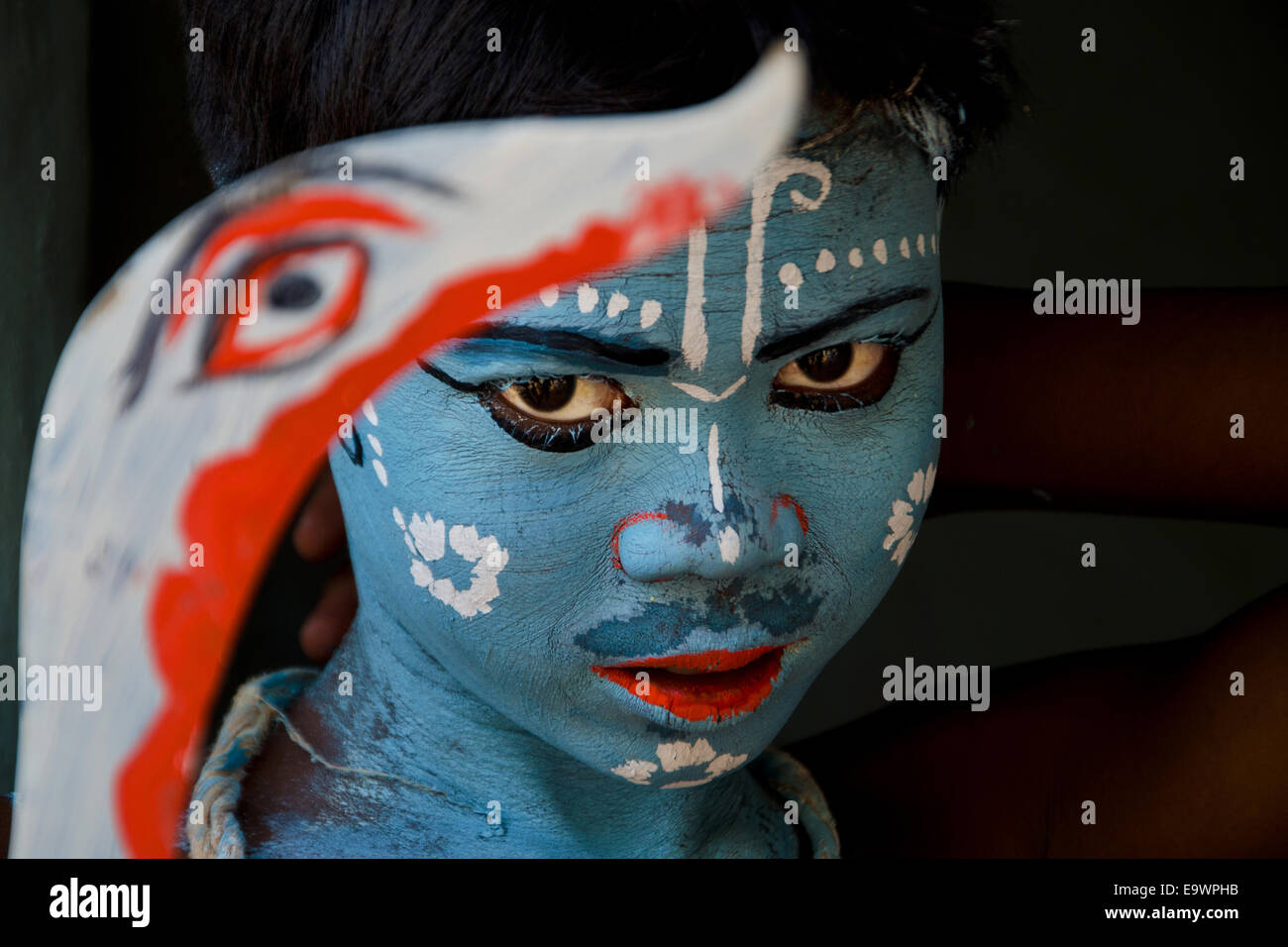 Boy holding sword with painted faces celebrating Gajan festival, Kolkata, West Bengal, India Stock Photo