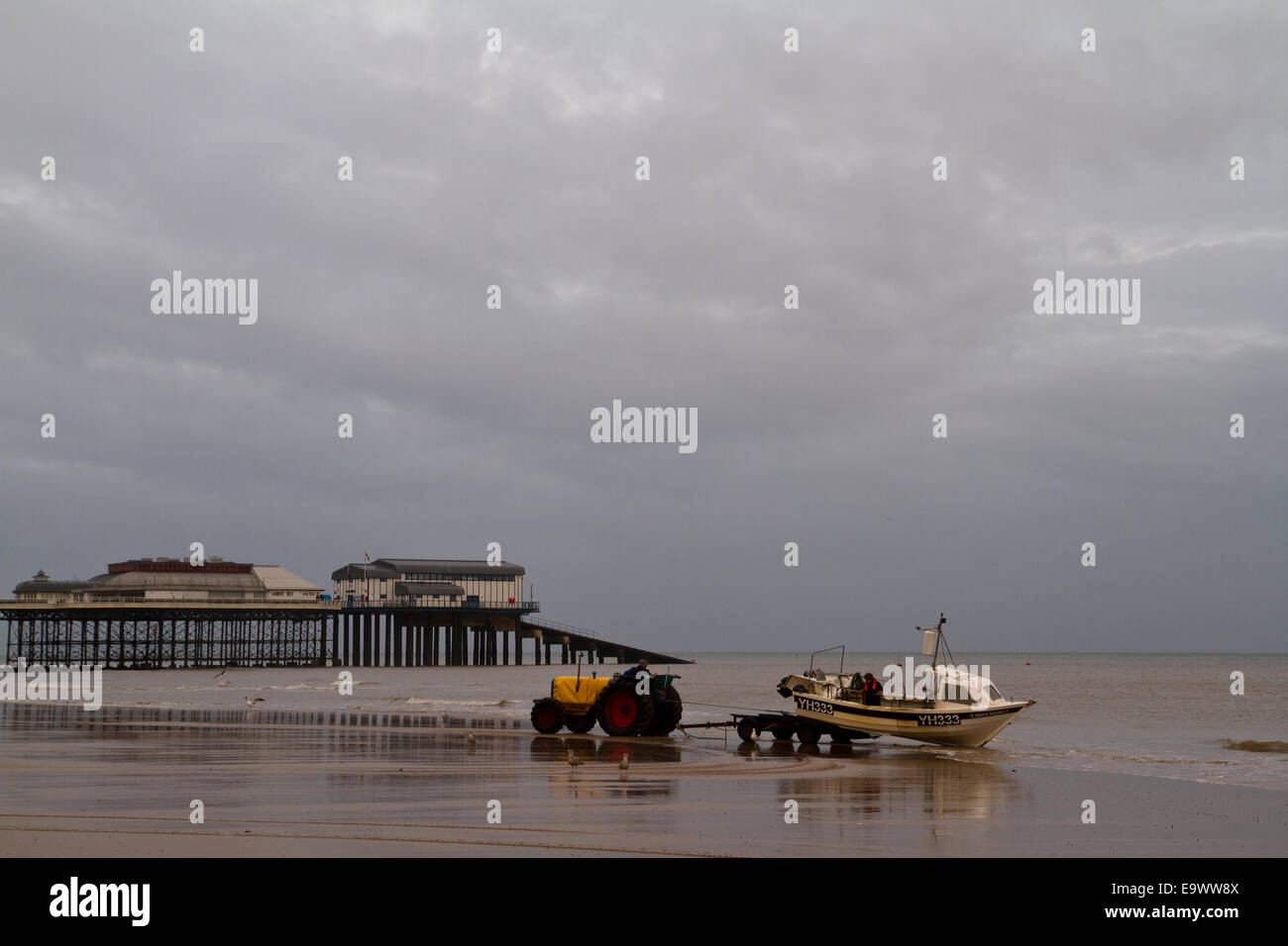 tractor retrieves fishing boat on Cromer beach in Norfolk Stock Photo