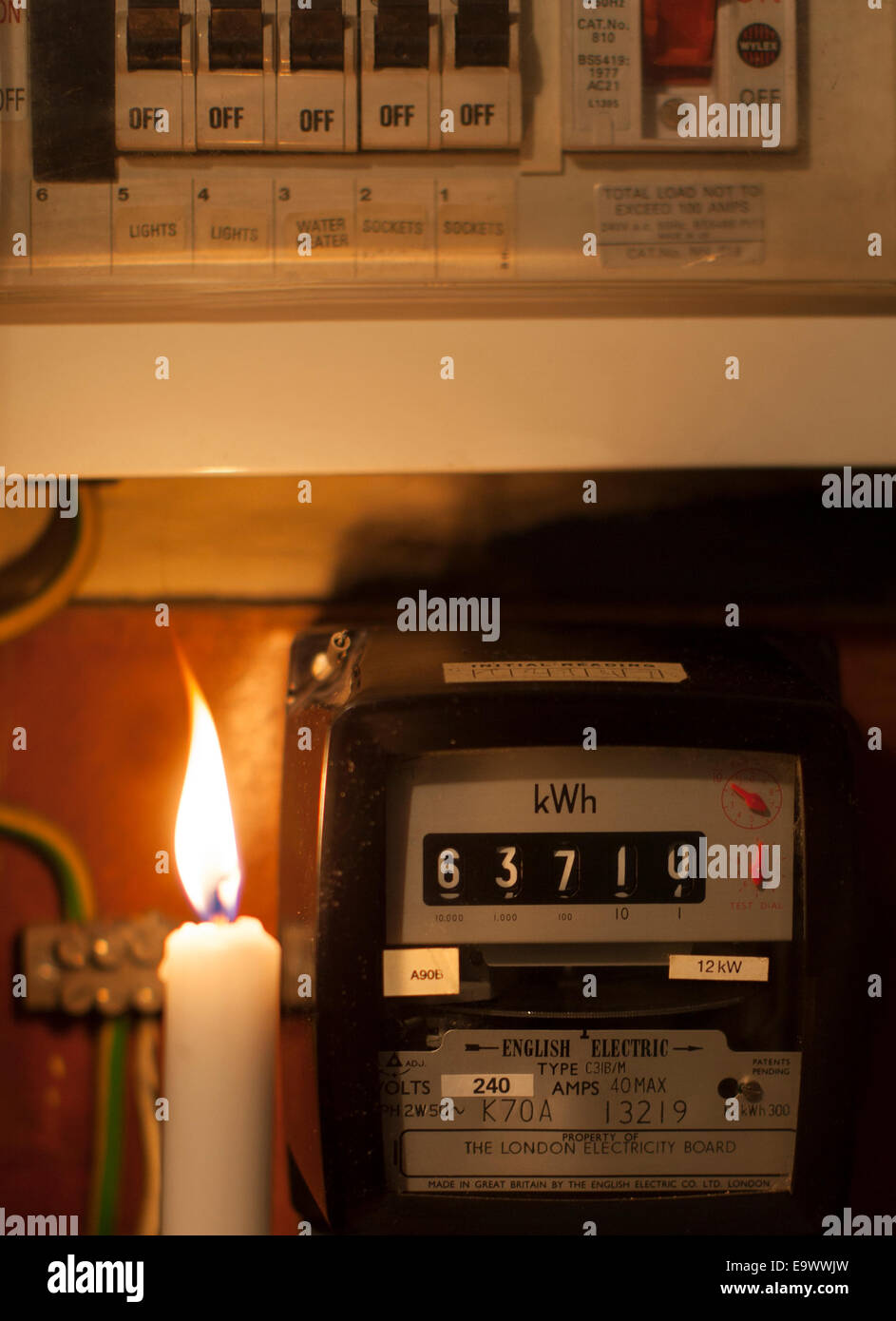 Electricity blackout: candle and electric meter in a home, London Stock Photo