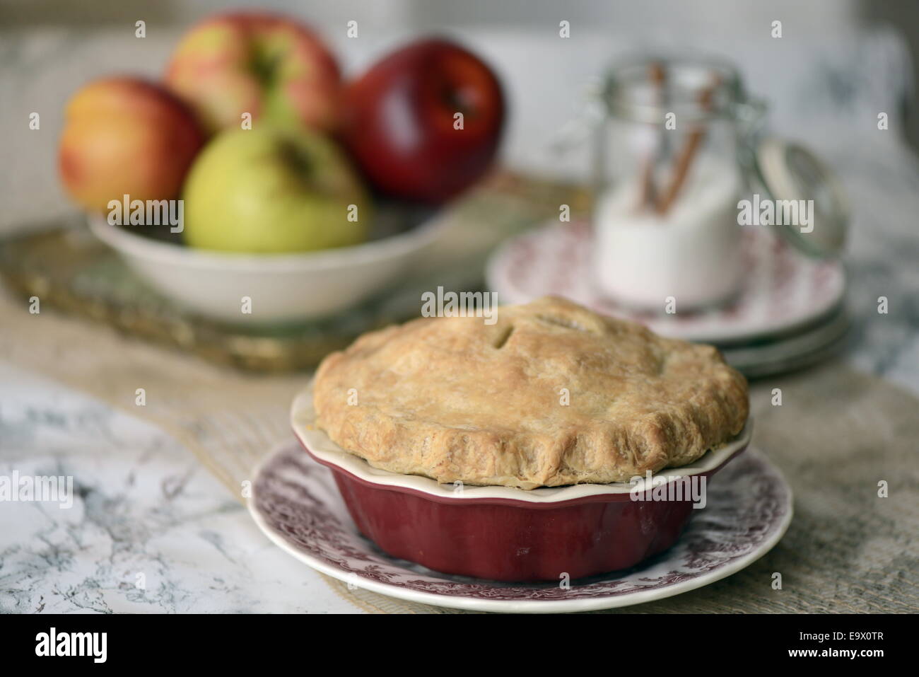 Home baked apple pie with fresh apples and cinnamon sugar in the background. Stock Photo