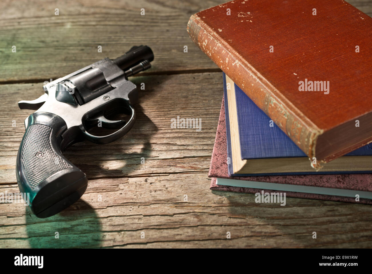 a gun with books on the wooden desk Stock Photo Alamy