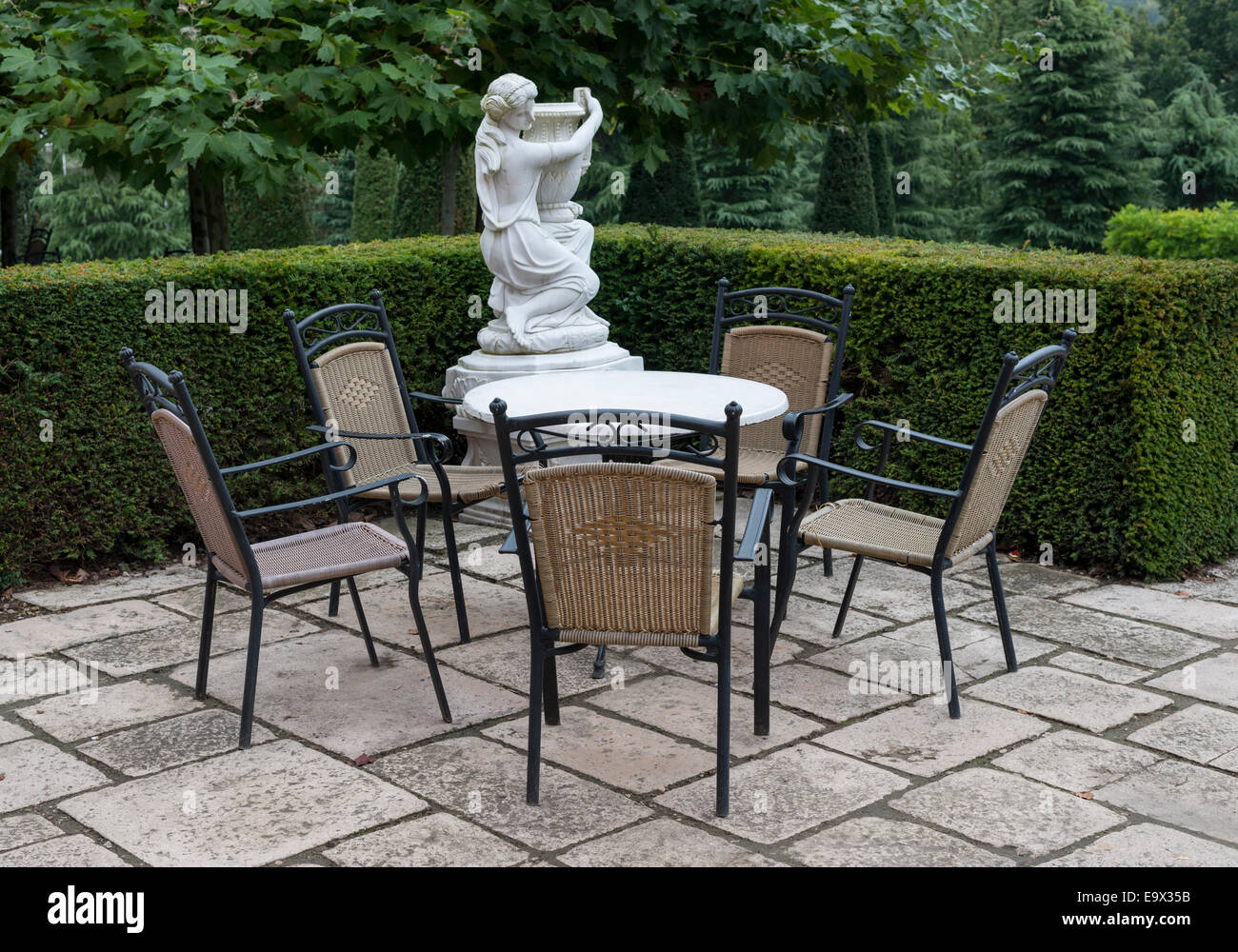 italian garden with chairs and table with white statue on background Stock Photo
