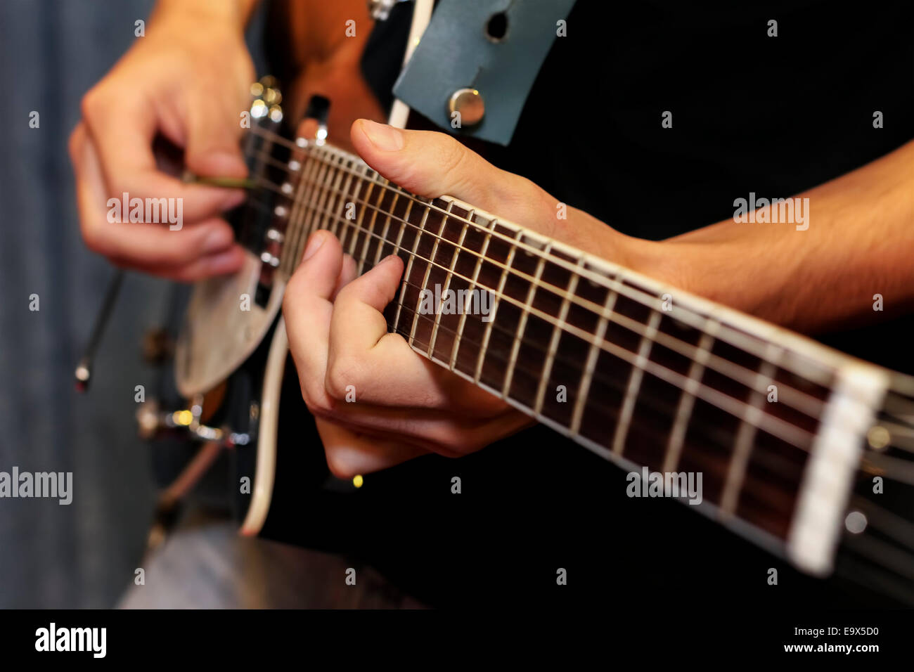 close up shot of a man with his fingers on the frets of a guitar playing Stock Photo