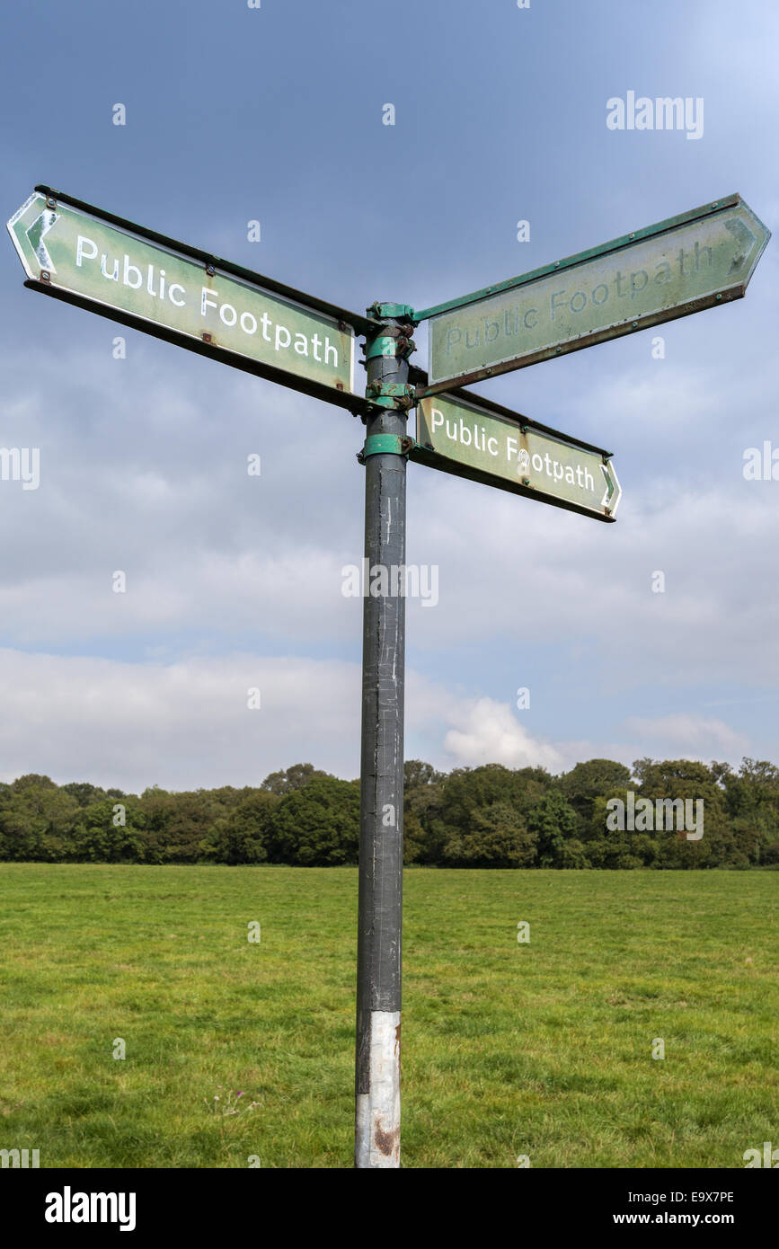 Public footpath sign pointing in three directions in the middle of the countryside Stock Photo