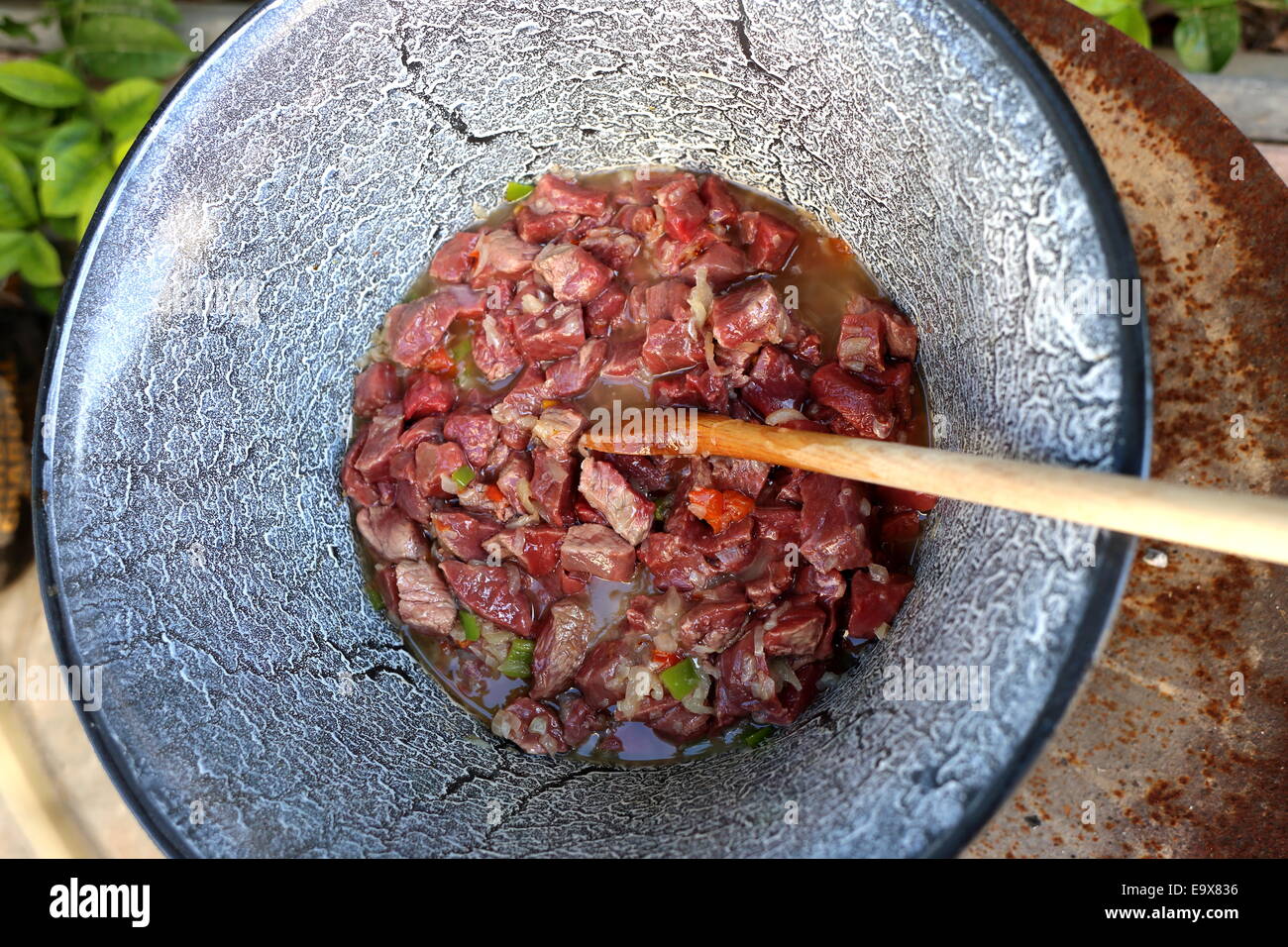 Making Hungarian goulash in a cauldron, bogracs, in the garden - cooking the meat Stock Photo