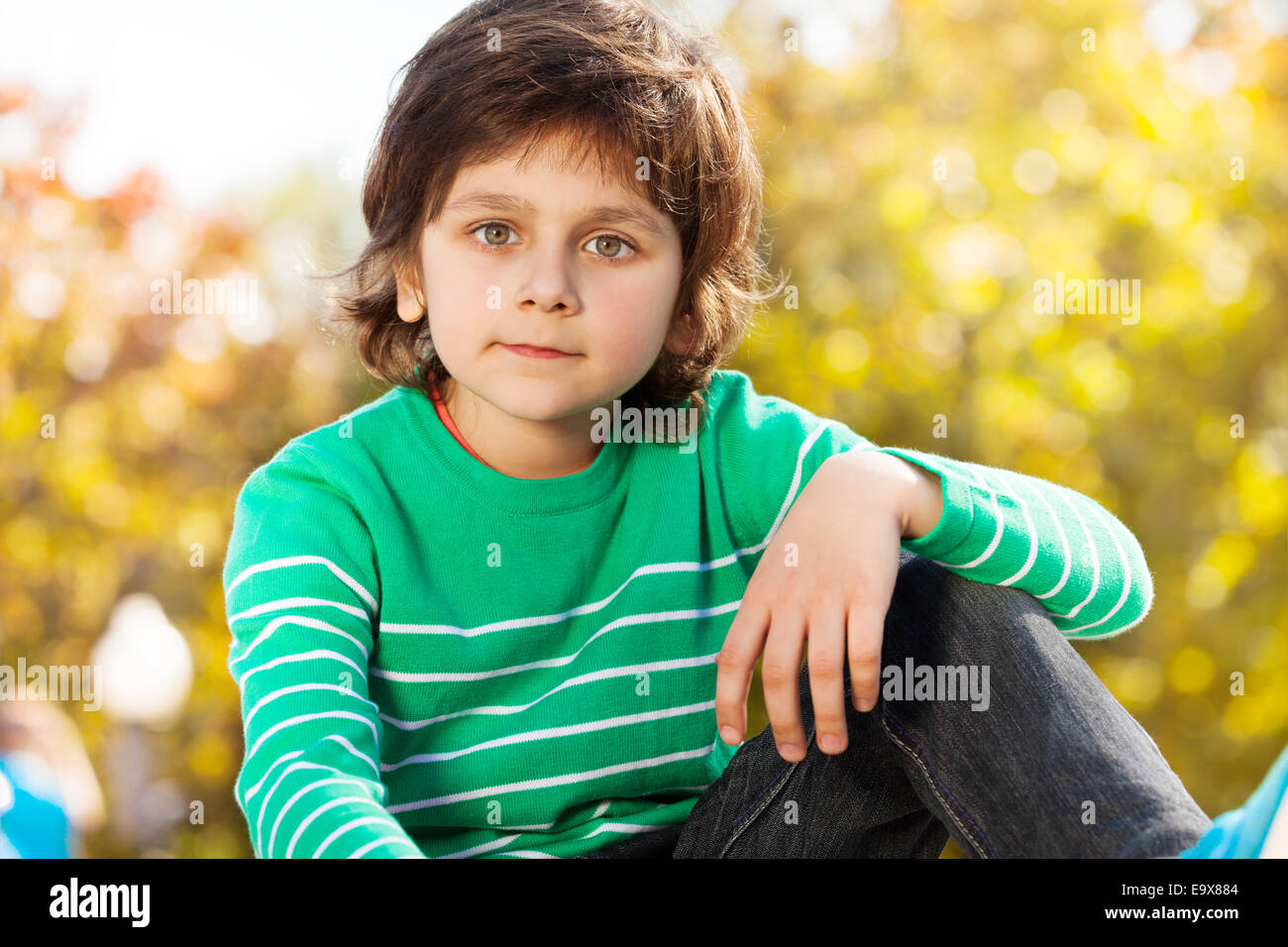 Cute boy in green sweater with arm on his knee Stock Photo Alamy