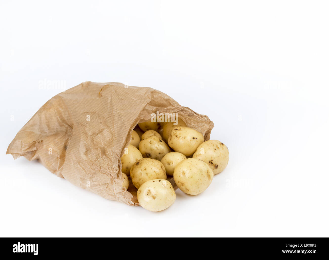New potatoes in brown bag on white background Stock Photo
