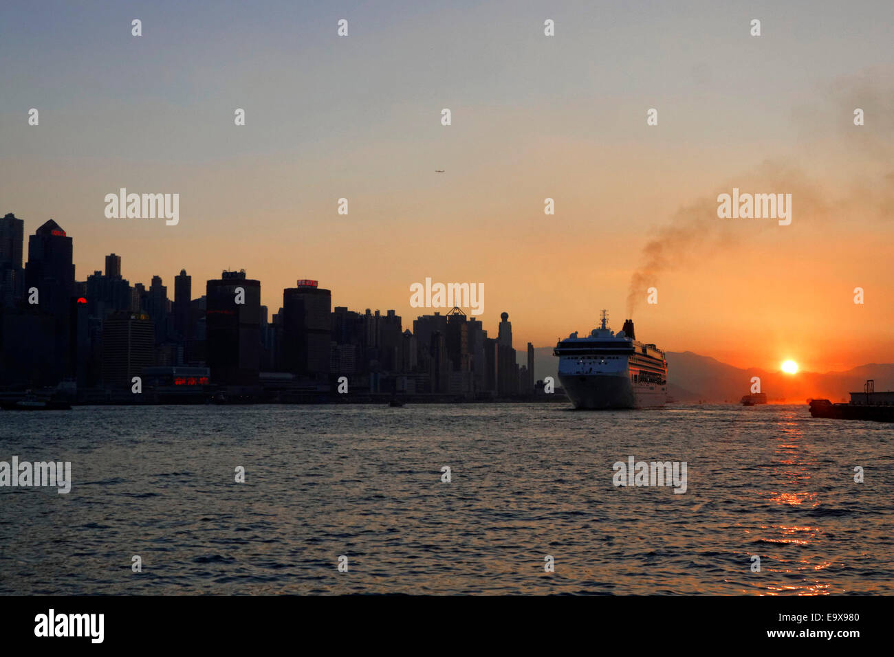A cruise ship depart Hong Kong harbour at sunset. Stock Photo