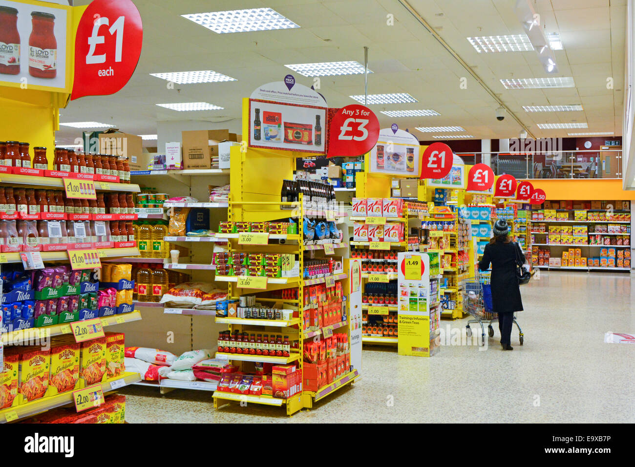 Tesco supermarket retail business interior with display stands flagged with red offer signs in this food and drink store London England UK Stock Photo