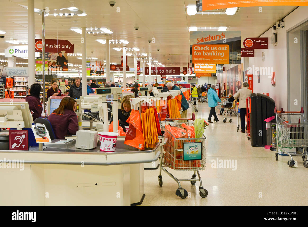 Sainsburys supermarket retail business checkout points for customer shoppers and staff at work in busy interior of store in Essex England UK Stock Photo