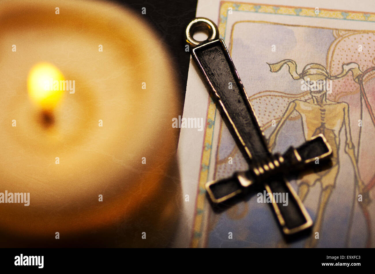 Inverted cross, tarot card and candle. Stock Photo