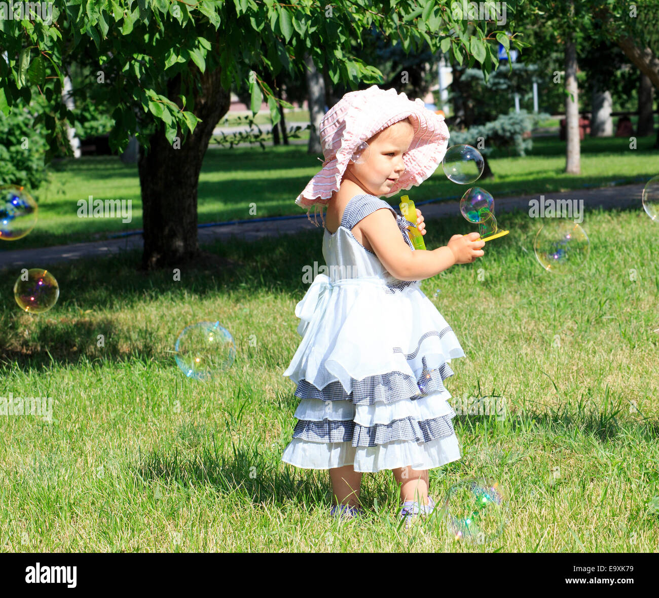Little girl blowing soap bubbles in city park Stock Photo - Alamy