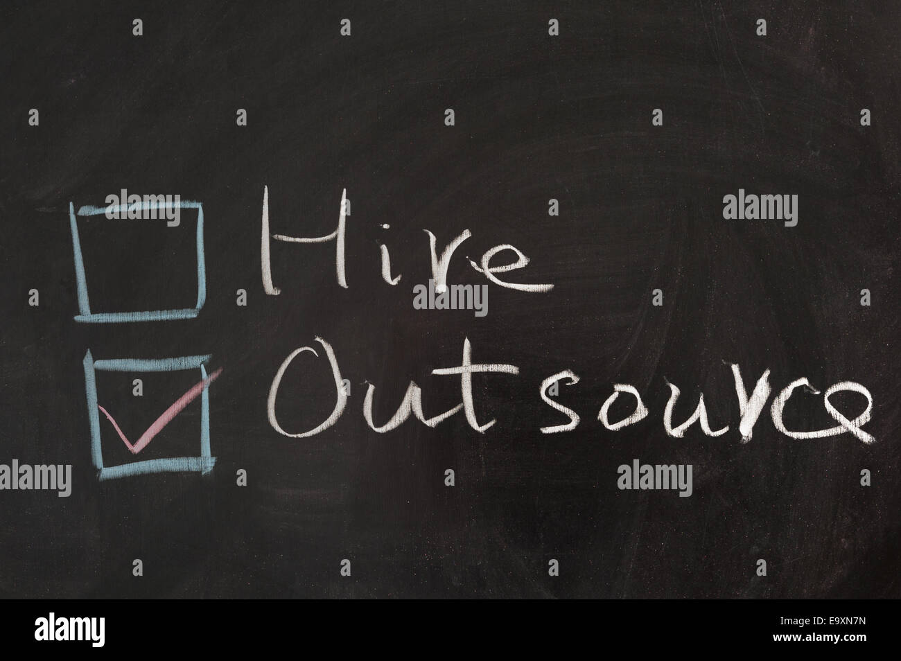 Choosing from hire and outsource concept words on blackboard Stock Photo